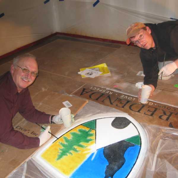 Darren and his father, Erni, painting a logo custom on the concrete floor